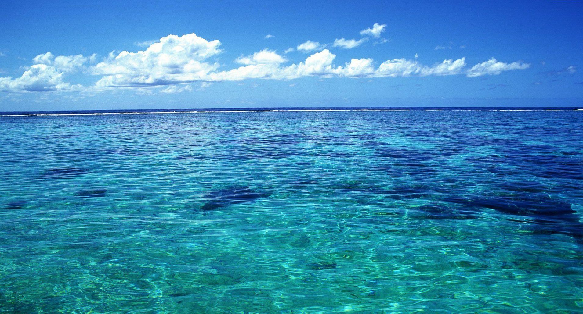 Clear turquoise ocean with distant horizon and clouds