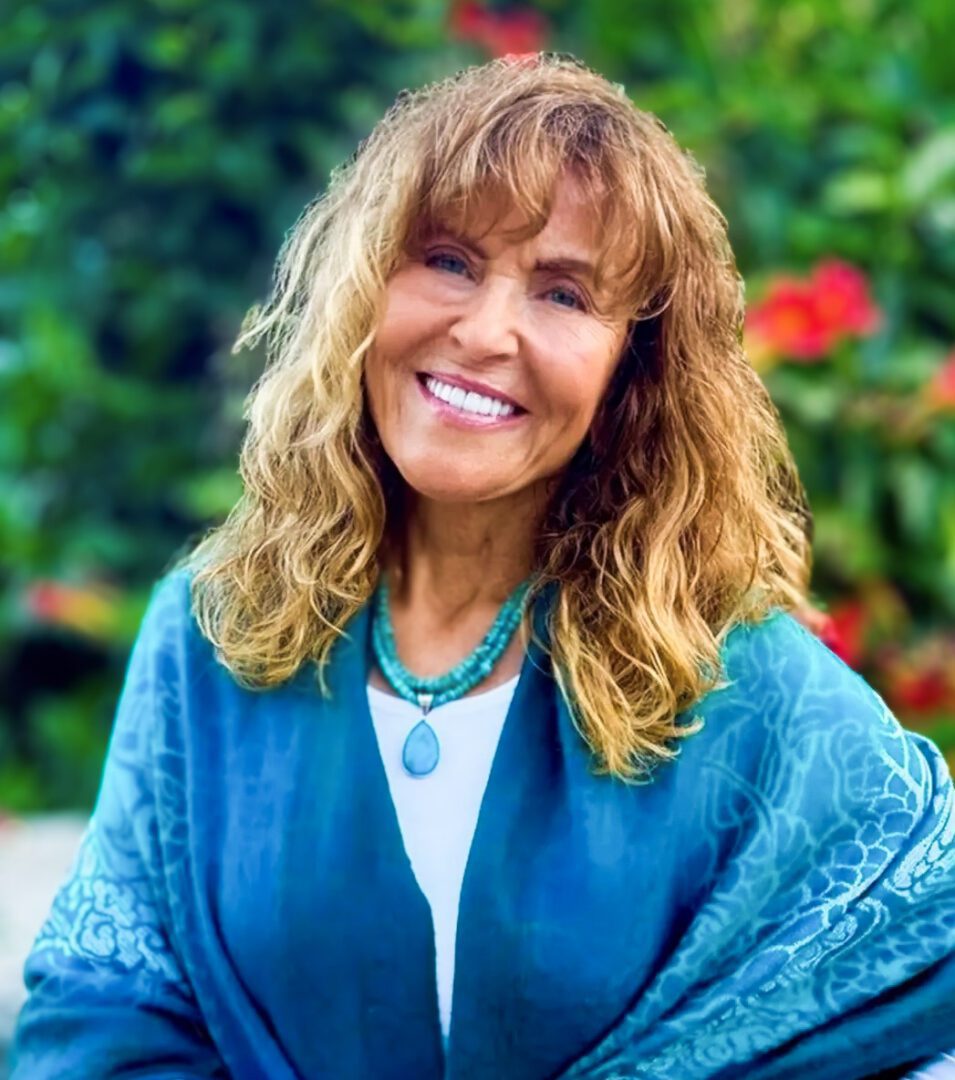 Smiling woman wearing a turquoise shawl outdoors.